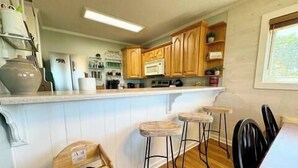 A kitchen with wooden cabinets, a white countertop, and a bar stool area. - 2120  Hot tub, sauna & more resort amenities Beautifully remodeled, 1st-floor (Beech Mountain)