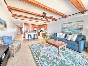 Ein geräumiger Wohnbereich mit einem blauen Sofa, einem Holztisch und einem gemusterten Teppich.
