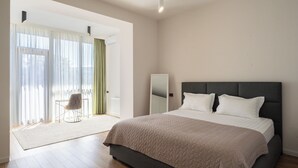 Un dormitorio con una cama grande, una silla, un espejo y vistas al exterior.