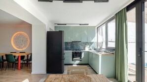 Una cocina moderna con comedor, ventanas amplias y un lámpara circular.