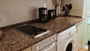 A kitchen with a built-in stove, a coffee maker, a washing machine, and a sink. - KATALIN (Lloret de Mar)