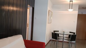 A room with a red sofa, a dining table with chairs, a framed picture on the wall, and a ceiling light fixture. - KATALIN (Lloret de Mar)