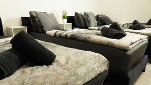 Une chambre d’hôtel avec deux lits, chacun agrémenté de draps noirs et beiges, de plusieurs oreillers et d’une petite plante en pot posée sur une table de chevet.