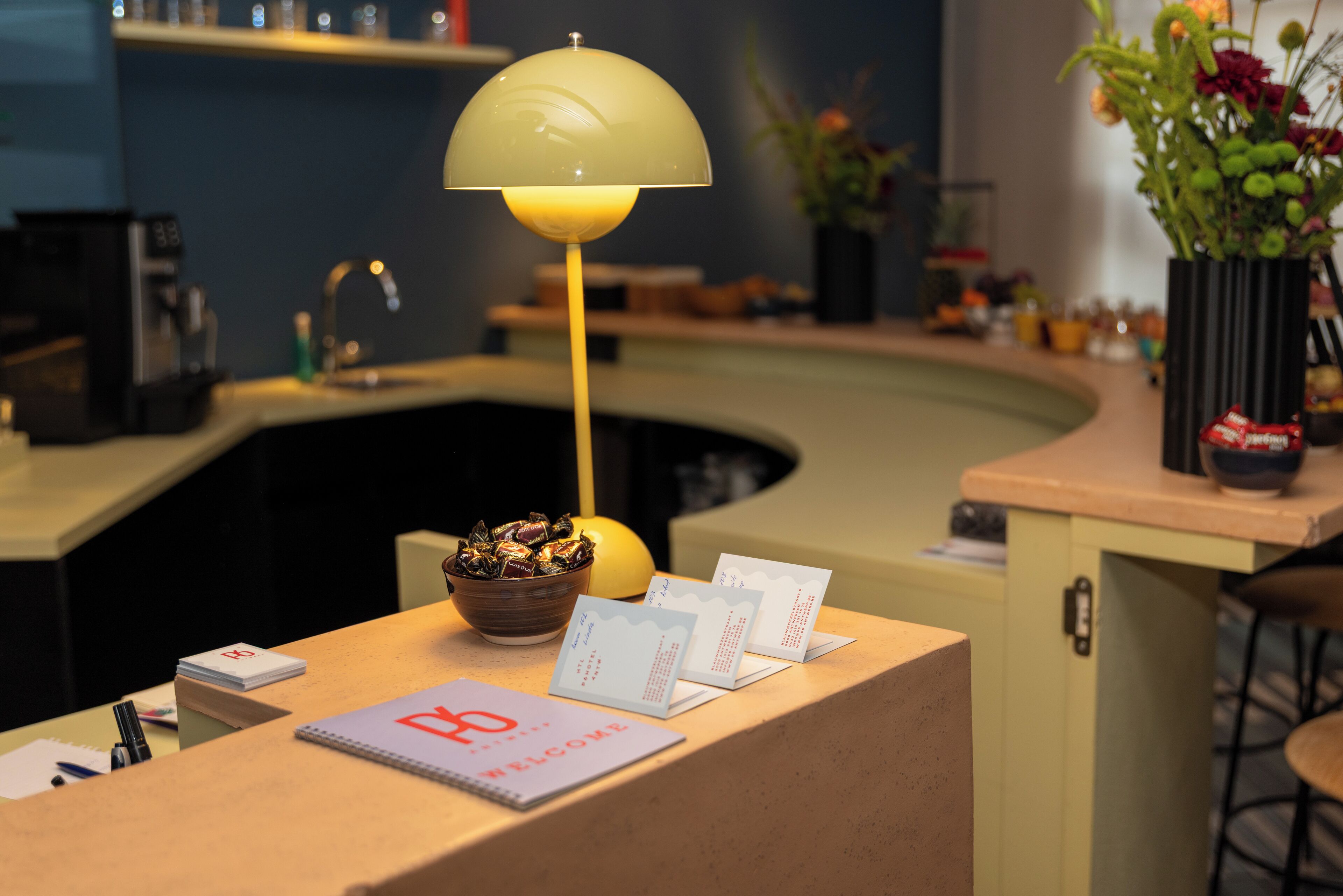 Een receptiebalie met een lamp, een schaal met snacks en welkomstkaarten.
