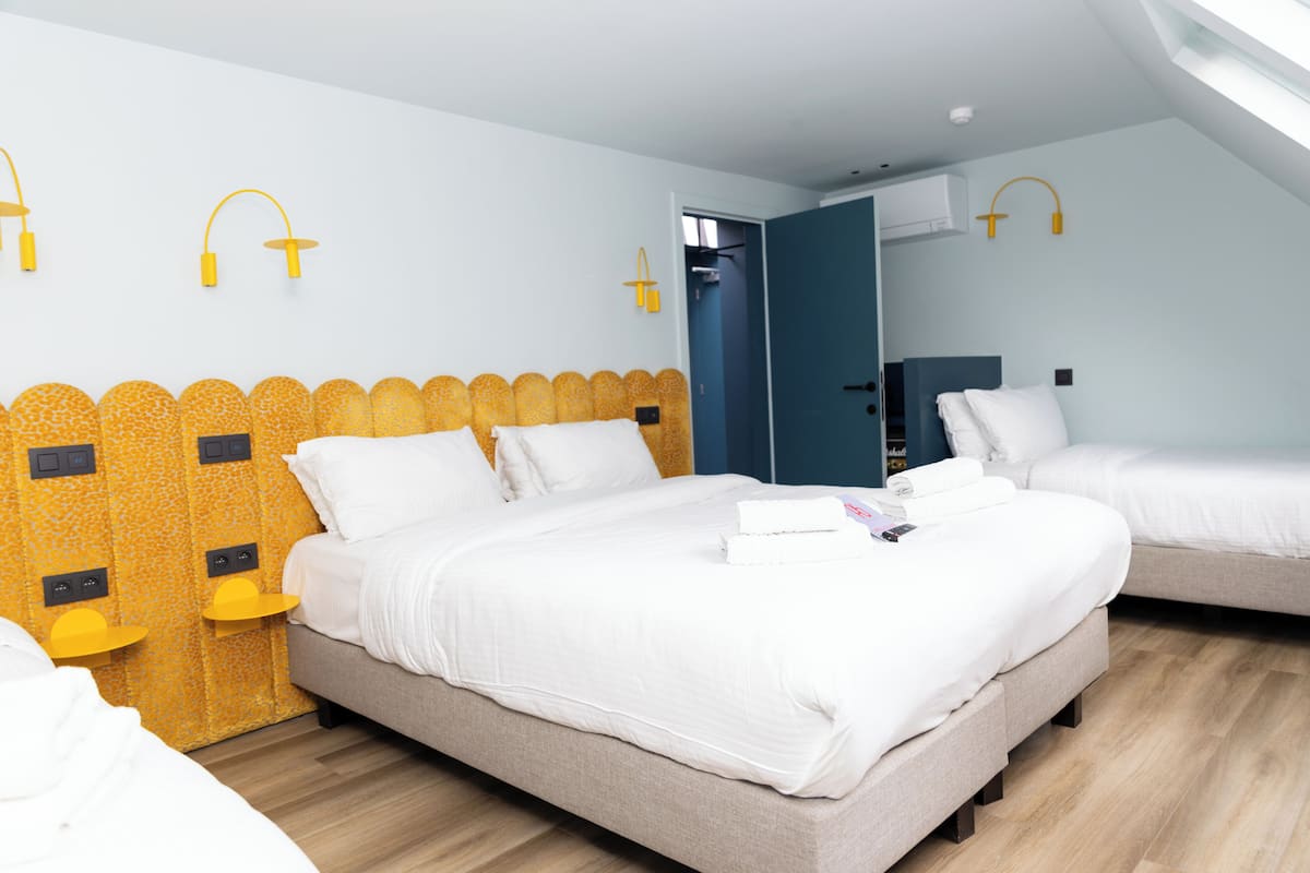 A modern hotel room with two beds, a wooden headboard, and a skylight.