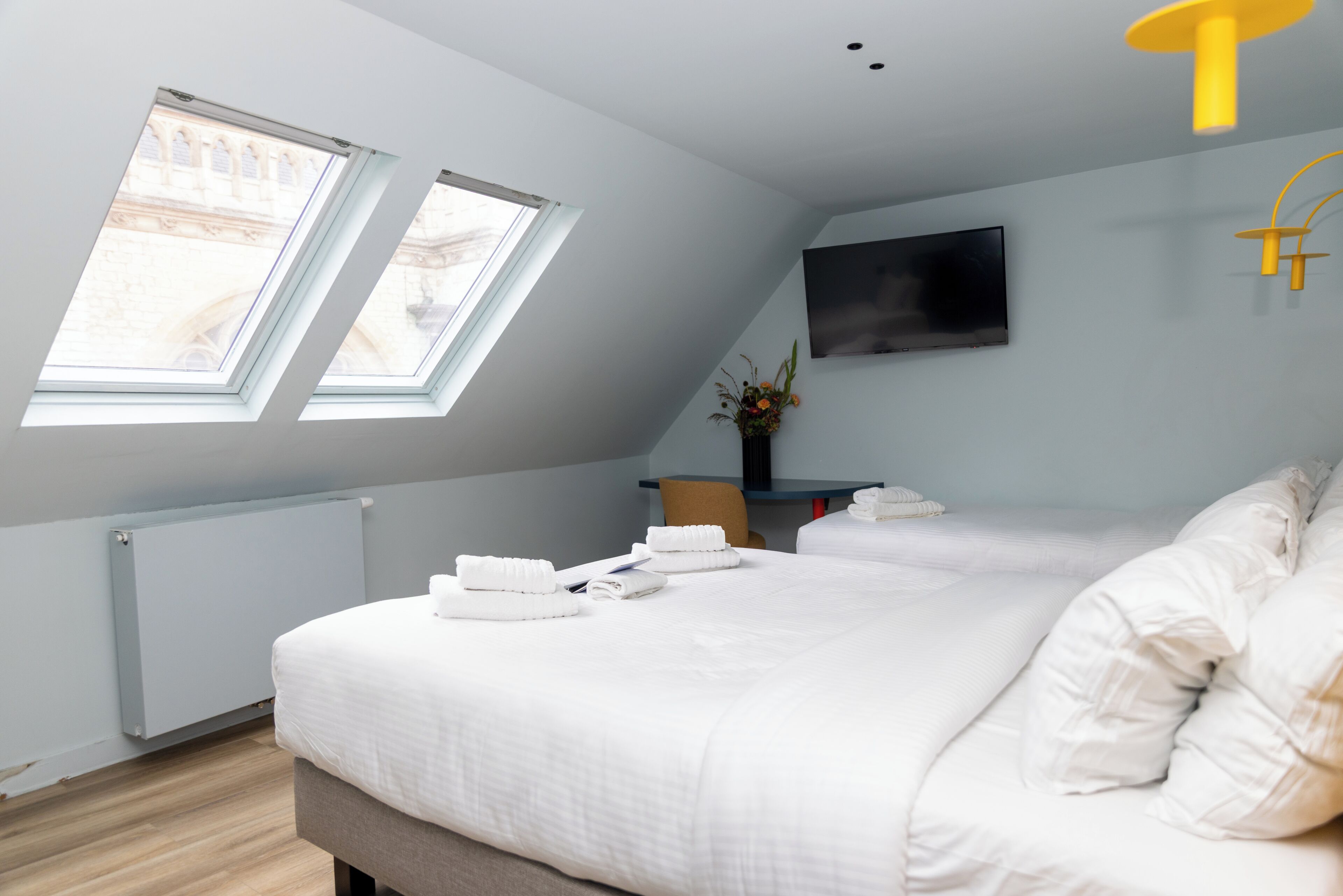 Un dormitorio moderno con una cama grande, tragaluces, un televisor de pantalla plana y un radiador.