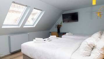 Un dormitorio moderno con una cama grande, tragaluces, un televisor de pantalla plana y un radiador.
