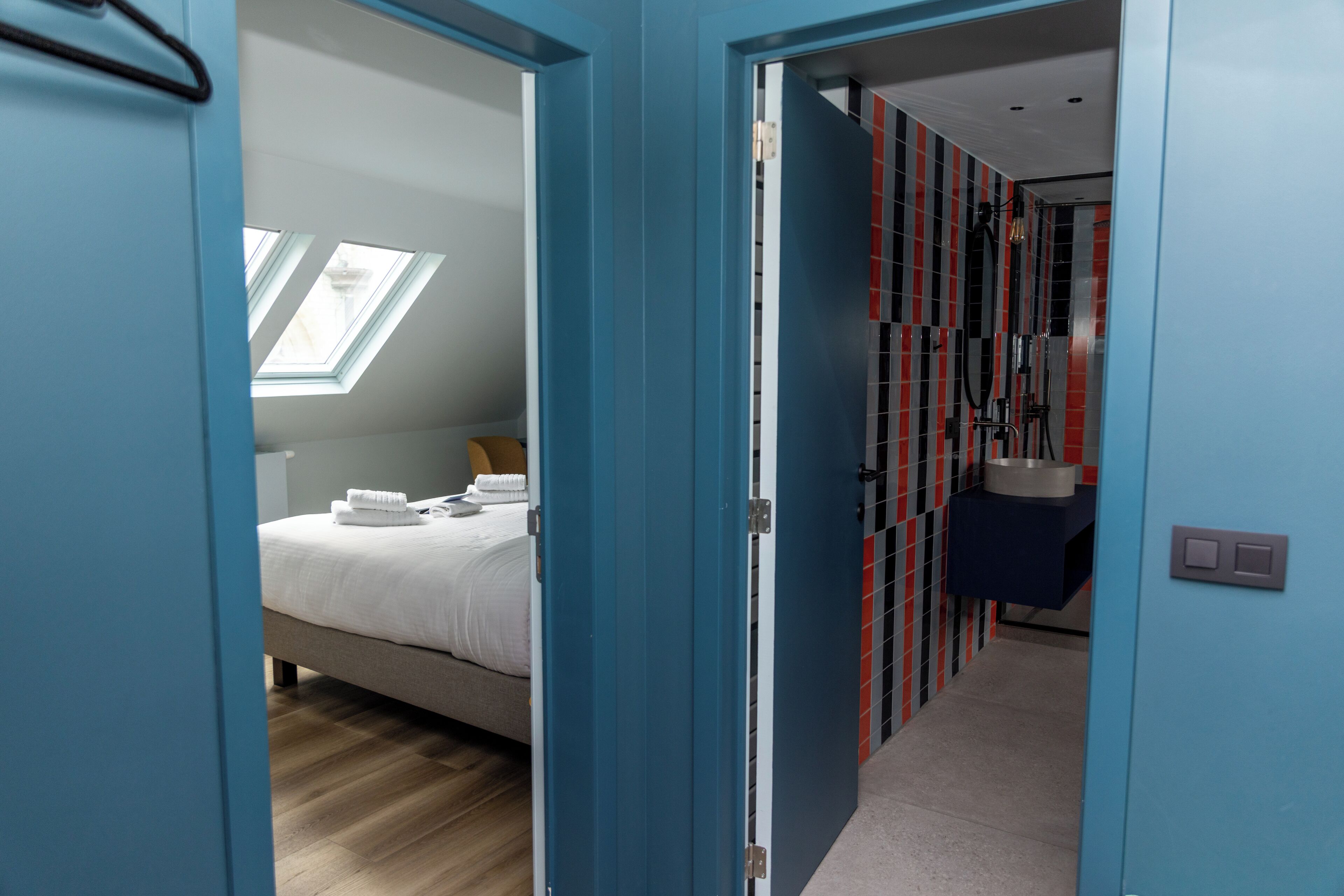 Et moderne hotelværelse med seng, skydeluge, badeværelse med bruser og gang med skabe.
