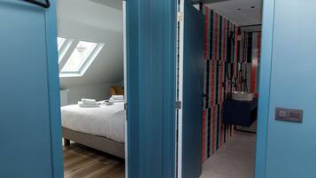 Et moderne hotelværelse med seng, skydeluge, badeværelse med bruser og gang med skabe.