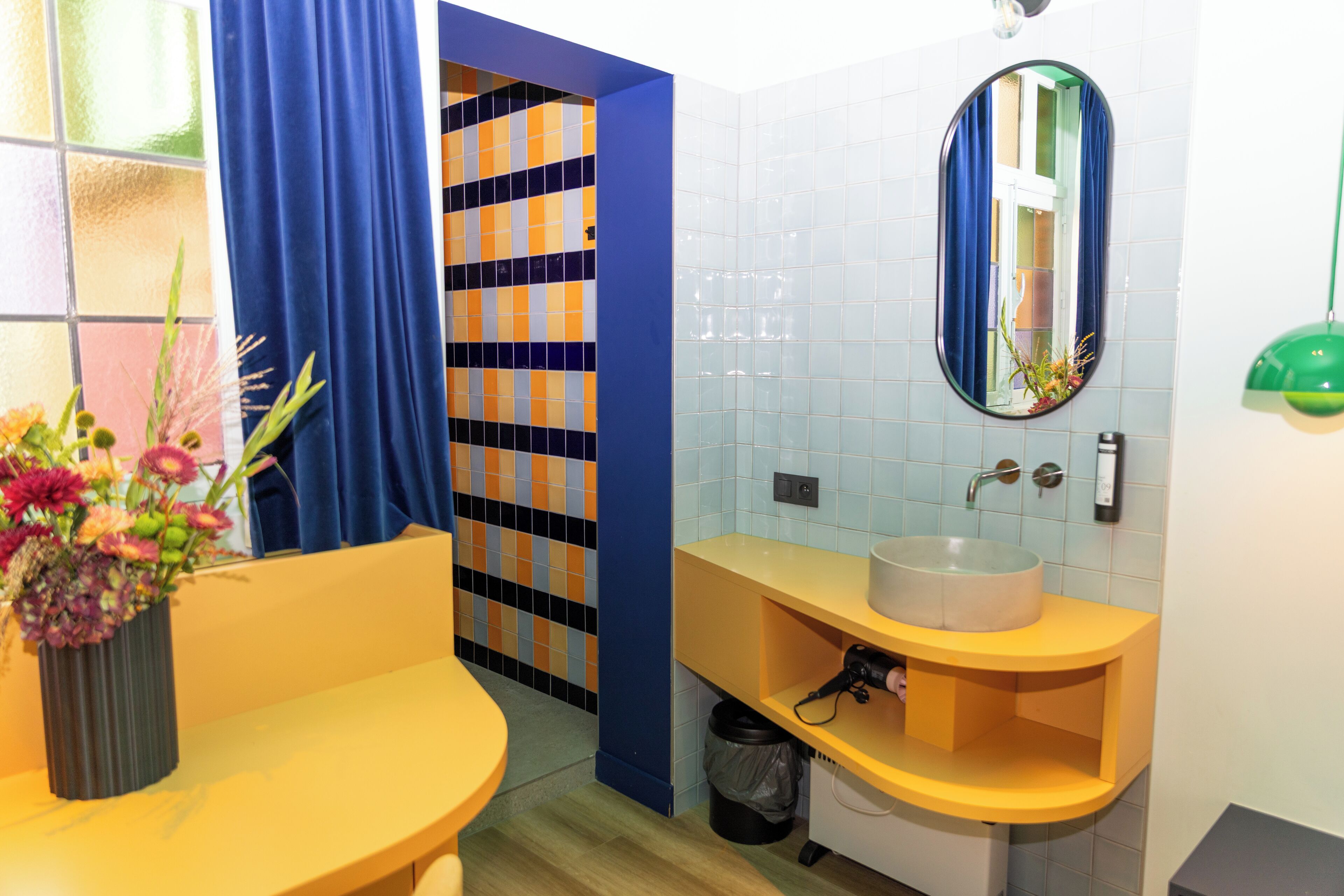 A bathroom with a yellow sink, blue curtains, and a tiled backsplash.