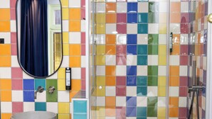 A bathroom with a colorful tiled wall, a round sink, a mirror, and a shower enclosure. - P6 Antwerp (Antwerp)