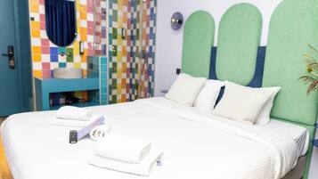 A hotel room with a bed, a bathroom with a colorful tile wall, and a green headboard.