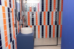 A bathroom with a white sink, blue countertop, and multicolored striped tiles.