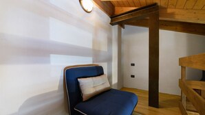A room with a blue sofa, a wooden ceiling, and a wall-mounted light fixture. - Room 'Stanza 1' with Mountain View, Wi-Fi and Air Conditioning (Marone)