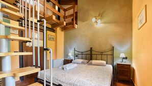 A bedroom with a bed, wooden headboard, bedside tables, and a staircase. - Room 'Stanza 1' with Mountain View, Wi-Fi and Air Conditioning (Marone)