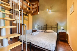 Une chambre à coucher avec un lit, une tête de lit en bois, des tables de chevet et un escalier.