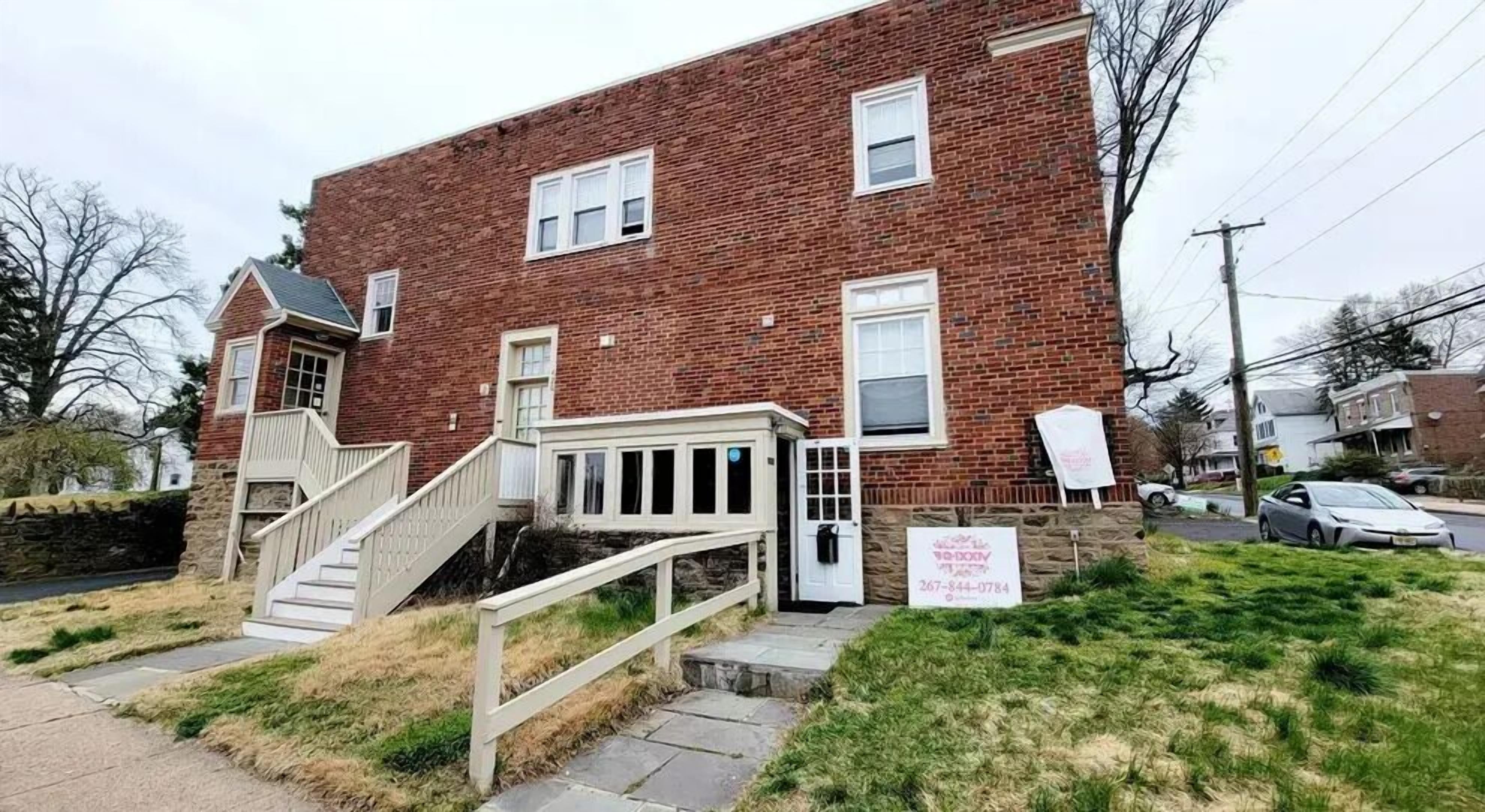 A two-story brick house with a front porch, a staircase, and a driveway.