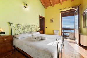 A bedroom with a bed, a nightstand, a dresser, a balcony with a view, and a wooden ceiling. - Room 'Stanza 2' with Lake View, Wi-Fi and Air Conditioning (Marone)