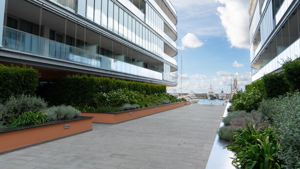 A modern building with multiple balconies, a paved walkway, and lush greenery. - Waterfront Suite by Wonderful Italy (Genoa)