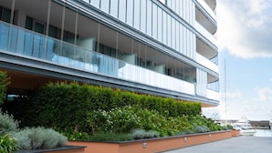 A modern multi-story building with balconies, a flat roof, and a landscaped area with plants. - Waterfront Suite by Wonderful Italy (Genoa)