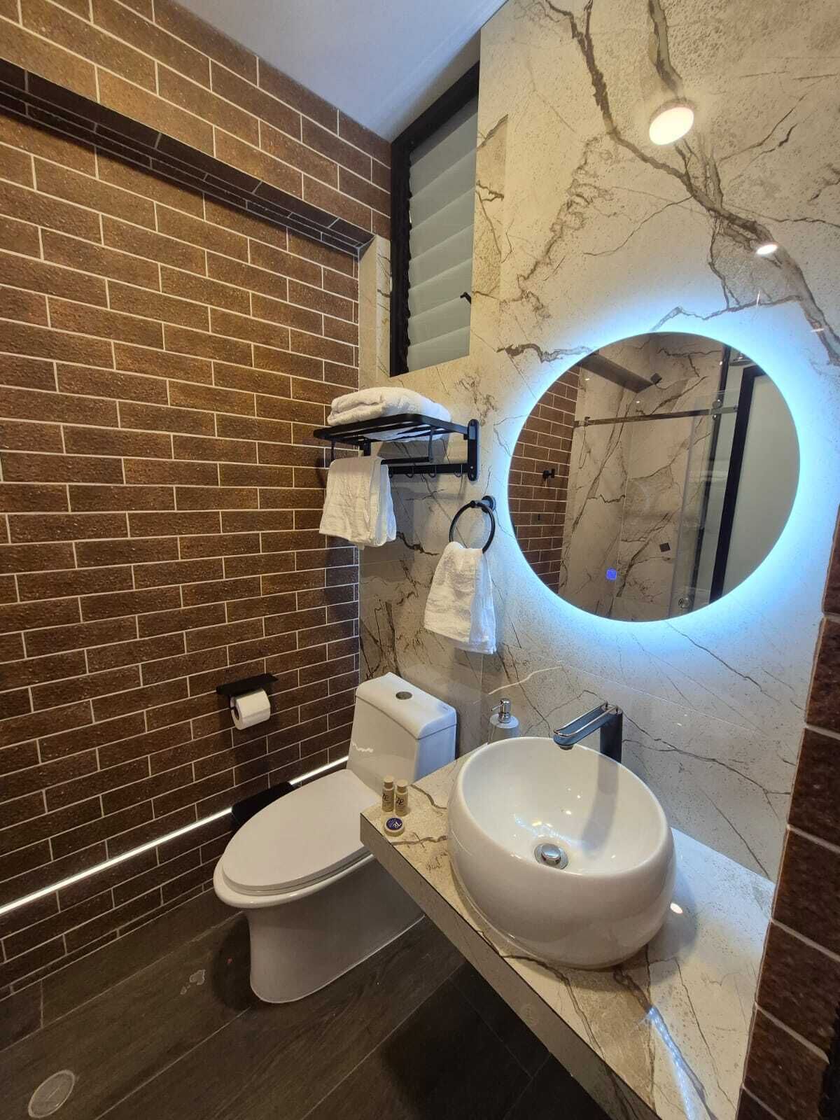 A modern bathroom with a marble vanity, a toilet, and a towel rack.