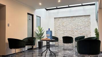 A modern interior with a stone wall, a water dispenser, and four dark chairs around a small table.