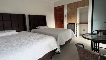 Ein modernes Hotelzimmer mit zwei Betten, einer Essecke und einer Küchenzeile.