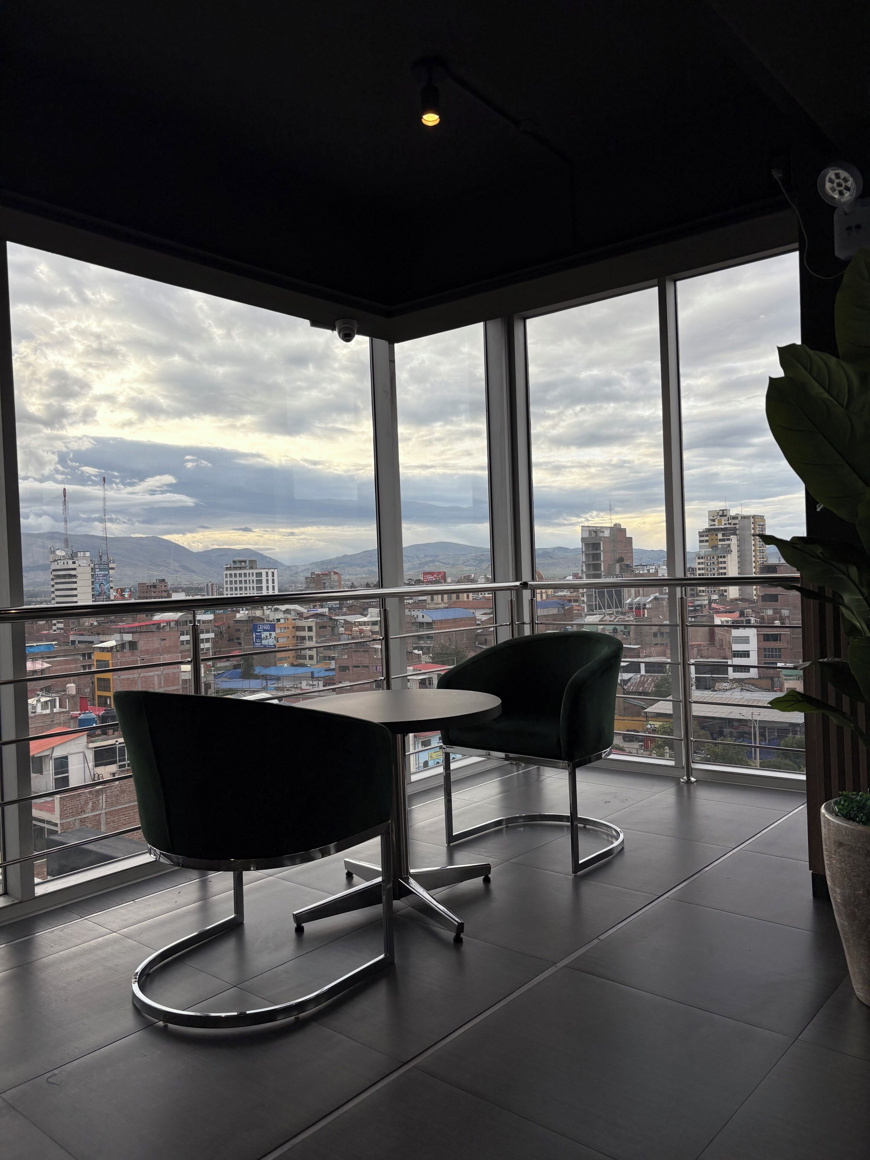 A modern room with a large window, a round table, two chairs, and a potted plant.