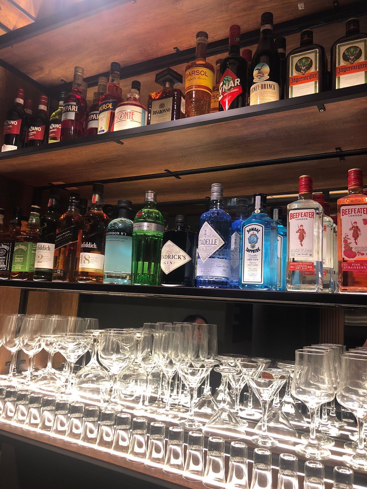 A bar with shelves of liquor bottles and a variety of glasses.