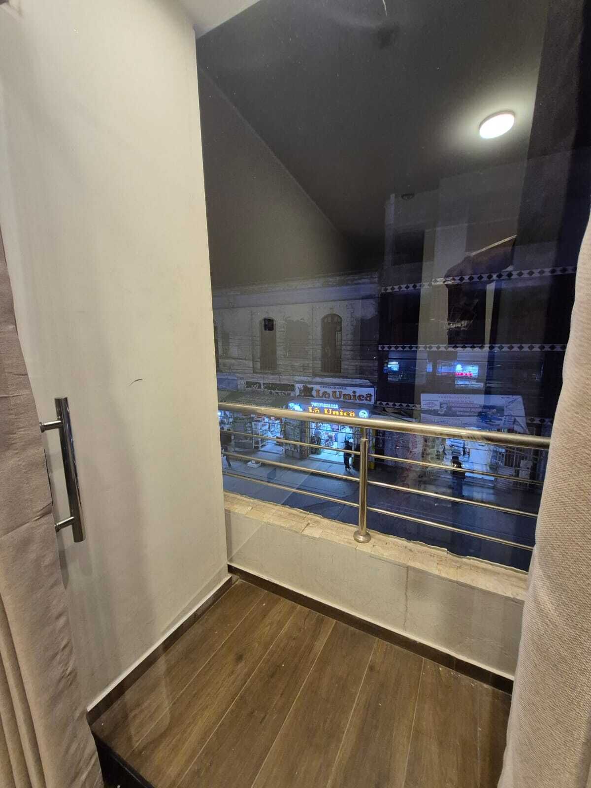 A view from a balcony with a metal railing, a wooden floor, and a glass wall.