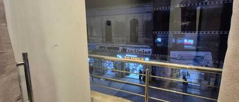 A view from a balcony with a metal railing, a wooden floor, and a glass wall.