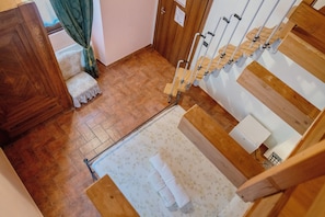 Un escalier en bois avec une rampe, un petit banc et un tapis à motifs sur le sol.