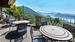 An outdoor patio with a round table and chairs, a yellow umbrella, and a scenic mountain view. - Room 'Stanza 5' with Mountain View, Wi-Fi and Air Conditioning (Marone)