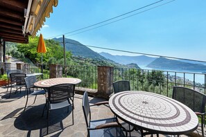 An outdoor patio with a round table and chairs, a yellow umbrella, and a scenic mountain view. - Room 'Stanza 5' with Mountain View, Wi-Fi and Air Conditioning (Marone)