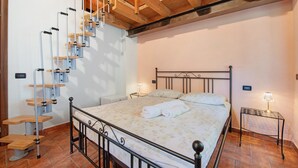 A bedroom with a bed, a wooden staircase, a nightstand, and a wall-mounted lamp. - Room 'Stanza 5' with Mountain View, Wi-Fi and Air Conditioning (Marone)