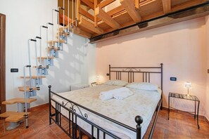 A bedroom with a bed, a wooden staircase, a nightstand, and a wall-mounted lamp. - Room 'Stanza 5' with Mountain View, Wi-Fi and Air Conditioning (Marone)