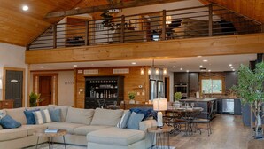 A spacious living area with a high ceiling, a dining area, and a kitchen. - Compass Retreat for large groups (Buchanan)