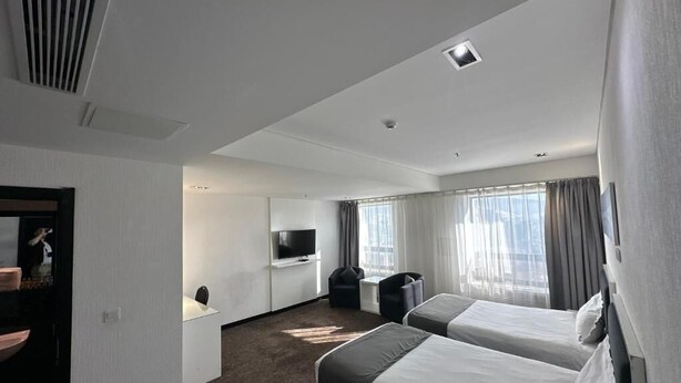 A hotel room with two beds, a desk, a TV, and a bathroom. - City Tower Hotel (Ulaanbaatar)