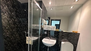 A modern bathroom with a glass shower enclosure, a white sink, and a toilet. - City Tower Hotel (Ulaanbaatar)