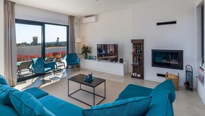 Een moderne woonkamer met een grote televisie, zithoek en uitzicht op de omgeving.