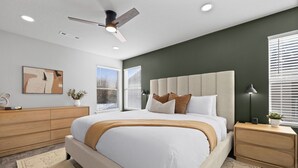 A modern bedroom with a large bed, a ceiling fan, a nightstand, and a window with blinds. - Basecamp - 3 miles to DT (Fayetteville)