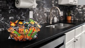 A kitchen with a black countertop, white cabinets, and a roll of paper towels. - Basecamp - 3 miles to DT (Fayetteville)