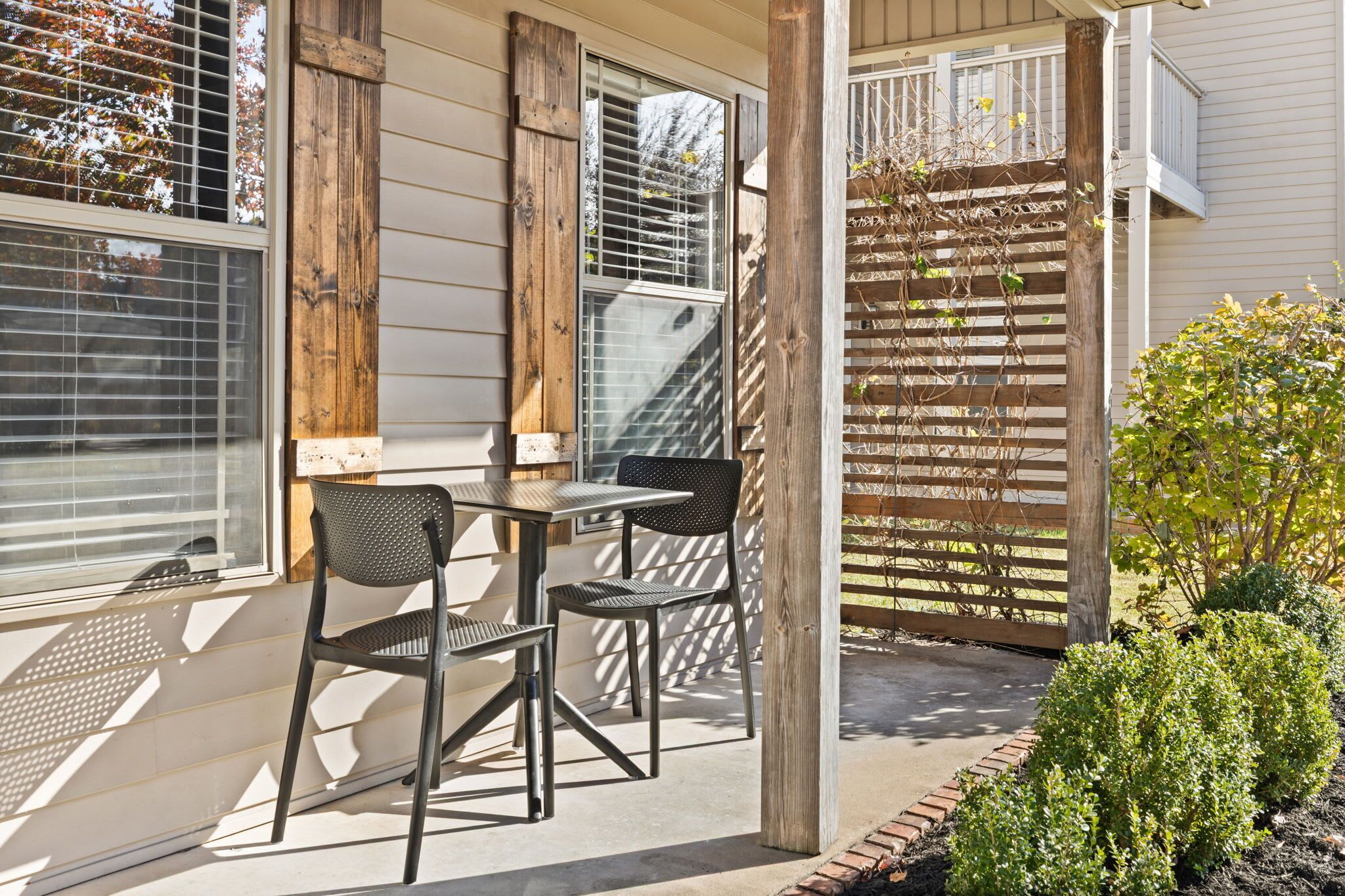 Une terrasse avec une table et des chaises, une clôture en bois et un petit jardin.