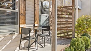 A patio with a table and chairs, a wooden fence, and a small garden. - Basecamp - 3 miles to DT (Fayetteville)