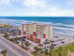 Ein Hotel mit Parkplatz, Blick auf den Strand und einer Straße im Vordergrund.