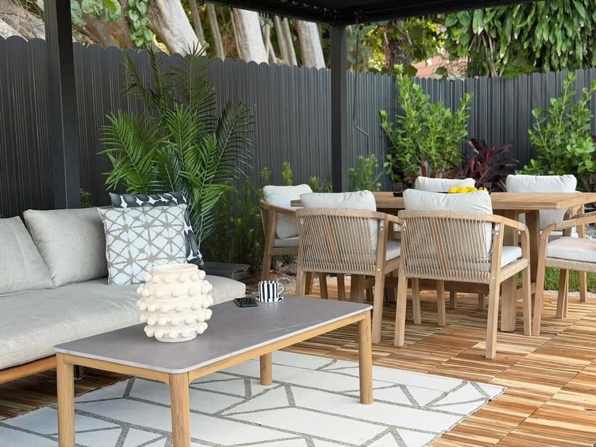 Un área de patio al aire libre con un sofá, una mesa de madera y sillas de mimbre.
