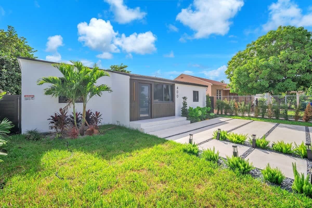A modern house with a white exterior, a number 400 sign, and a well-maintained garden with grass and plants.