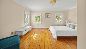 Un dormitorio con una cama grande, un banco y dos ventanas.