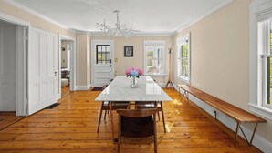 Comedor con una mesa de mármol, sillas de madera, un banco y una araña.