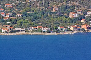 Eine Küstenstadt mit Häusern entlang der Uferlinie, einem Strand und einer hügeligen Kulisse.